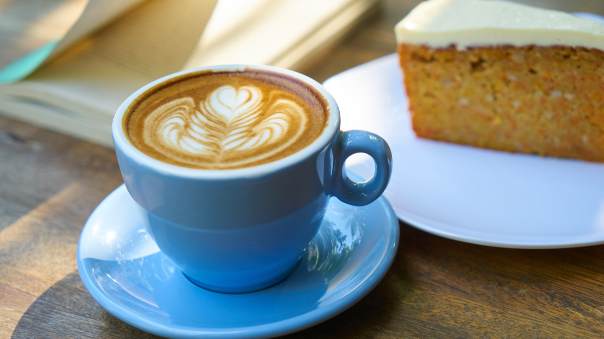 Coffee in a blue cup and saucer with a slice of cake.