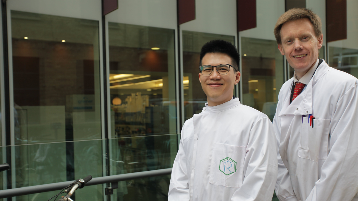 Bryan and Roland standing in front of windows in lab coats