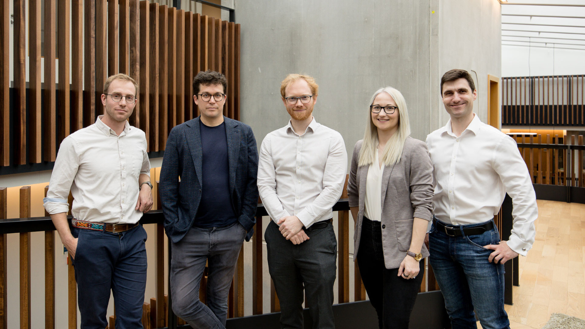 Five people standing together inside a modern space