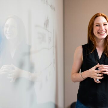 A woman standing in front of a white board