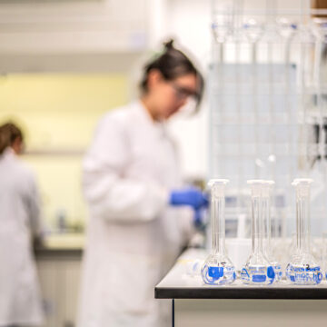 A row of test tubes in a laboratory with scientists working in the background