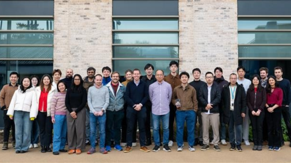 A research group standing in front of a new building